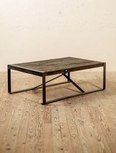 a wooden table sitting on top of a hard wood floor next to a white wall