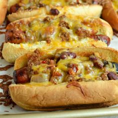 three hot dogs on buns covered in cheese and chili