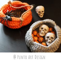 two crocheted baskets with skulls and pumpkins in them sitting on a table