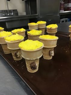 ice cream cones with yellow frosting are lined up on a counter