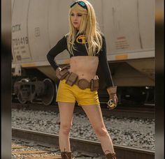 a woman standing on train tracks in yellow shorts