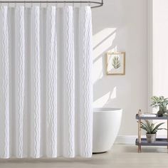 a white shower curtain in a bathroom next to a bathtub and potted plant