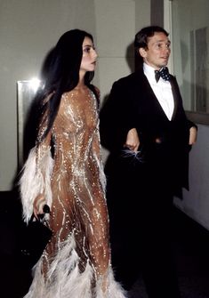 the man and woman are dressed up in black tuxedo, feathers, and sequins