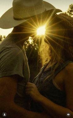 a man and woman kissing in front of the sun