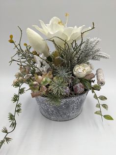 a metal bucket filled with flowers and greenery