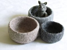 three felt bowls are sitting on the floor with a toy rhinoceros in them