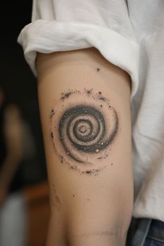 a person's arm with a tattoo on it that has an image of a black and white spiral