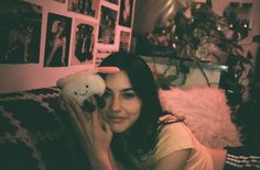 a woman laying on top of a bed holding a stuffed animal next to her face