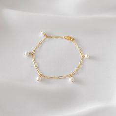 "A dainty link chain bracelet featuring 5 pearl dangles. Pearls are genuine freshwater pearls in a slightly off-round shape. Be sure to measure your wrist if you are going for a tight fit like the model who is wearing the 5.75 inches. Otherwise, the standard length at department stores for women's bracelets is 7 inches. This item is 14k gold filled and is tarnish-resistant, water-resistant, and hypoallergenic. --------------------♥ PROMOS ♥-------------------- Want 10% off? Join the mailing list Minimalist White Jubilee Chain Bracelet, Minimalist White Bangle Chain Bracelet, Dainty White Bangle Charm Bracelet, White Dainty Bracelets With Adjustable Chain, White Dangle Charm Bracelet With Lobster Clasp, Gift Pearl Charm Dangle Bracelets, Pearl Charm Dangle Bracelets As Gift, Dainty White Chain Bracelet With Extender, Dainty Adjustable Dangle Charm Bracelet