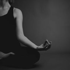 a woman is sitting in the middle of a yoga pose with her hands crossed out