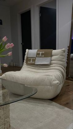 a white couch sitting on top of a wooden floor next to a vase filled with flowers