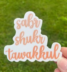 someone holding up a sticker that says sabar shukr tawakkil