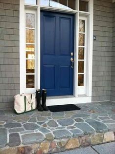 a blue front door with white trim and two black boots on the steps next to it