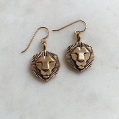 The king of the jungle! Each lion charm measures approximately 3/4" x 3/4" and hangs from gold filled or sterling silver ear wires. Made by hand in our south Louisiana studio.Each piece varies slightly due to its handmade nature. Lion Earrings, Lion Charm, Tiger Pendant, Lion Pendant, King Of The Jungle, South Louisiana, Ear Candy, Birthstone Bracelets, Birthstone Earring