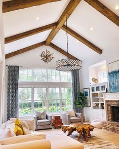 a living room filled with furniture and a fire place under a wooden beamed ceiling