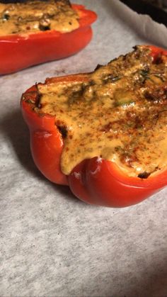 two stuffed peppers sitting on top of a baking sheet