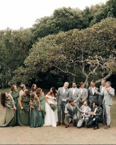 a large group of people standing next to each other in front of trees and bushes