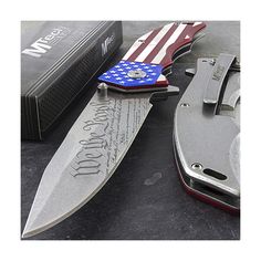 an american flag pocket knife next to a pair of knives with writing on it and a box in the background