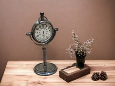 a clock sitting on top of a wooden table next to a vase with white flowers