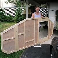 a woman is standing in the doorway of a house made out of wooden planks