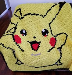 a yellow crocheted blanket with an image of a pikachu on it