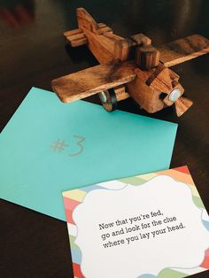 a wooden toy airplane sitting on top of a table next to a card and envelope