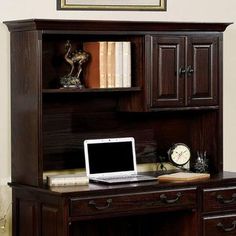 a laptop computer sitting on top of a wooden desk next to a book case and clock