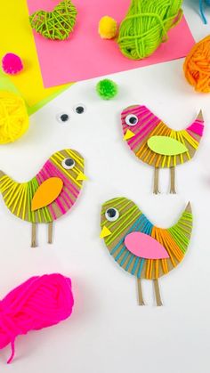 paper birds made from yarn and yarnsticks sitting on top of a white table