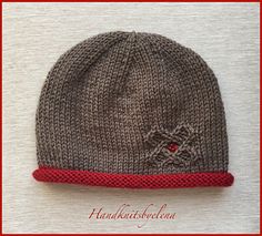 a knitted hat with a red band around the brim and an embellishment