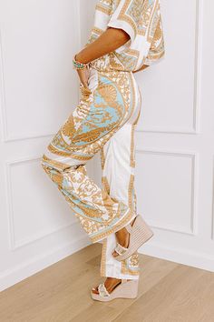 - Step into the spotlight with these fabulous satin-finished pants! Its charming relaxed fit is both trendy and classy, while the ornate print adds a dash of elegance and fun. Perfect for any occasion, this piece is your new go-to for effortlessly chic energy. - Fully lined material with an ornate print featuring mustard, blue, and neutral hues and satin finish - Side zip closure - Functional side pockets - A relaxed silhouette that ends in straight hemlines Measurements S : Front Rise 12.5", Hi White Satin Bottoms For Summer, Beige Satin Bottoms For Spring, Elegant Printed Summer Pants, Gold Chic Sets For Spring, Chic Gold Sets For Spring, Ankle-length Printed White Pants, Elegant White Printed Bottoms, Retro Revival, Short One Piece