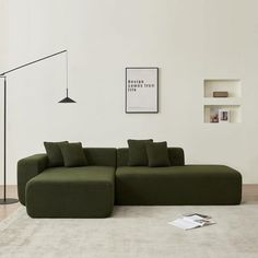 a large green couch sitting on top of a white rug next to a floor lamp