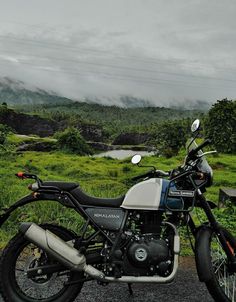 the motorcycle is parked on the side of the road in front of some green hills