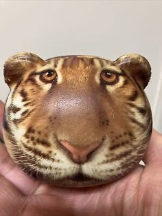 a close up of a person holding a fake tiger head in their hand and looking at the camera