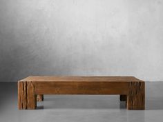 a wooden bench sitting on top of a cement floor next to a wall with concrete walls in the background