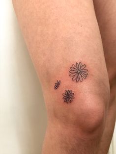 a woman's thigh with three small flowers on it