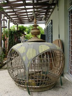 a bird cage sitting on top of a patio next to a building with a roof