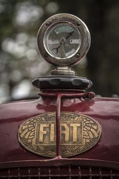 an old red car with the word fiat on it's front grill and clock