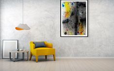 a yellow chair sitting in front of a painting on the wall next to a lamp