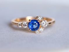 a blue and white diamond ring with three diamonds on the side, set in yellow gold