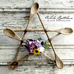 wooden spoons and flowers are arranged in the shape of a star on a wall