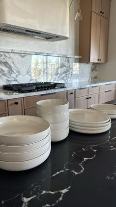 a kitchen counter topped with white plates and bowls