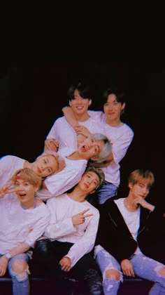 the group of young men are posing together for a photo in front of a black background