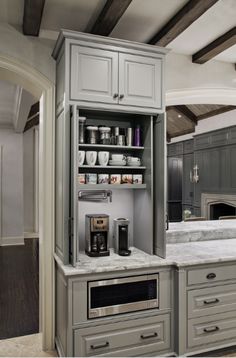 a kitchen with gray cabinets and marble counter tops, along with an open coffee bar