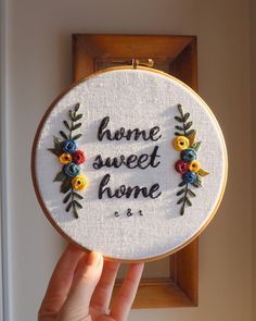 someone is holding up a cross - stitch hoop with the words home sweet home on it