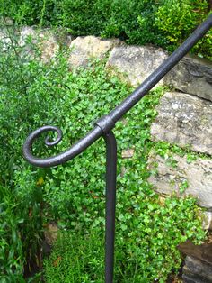 an iron handrail in front of some green plants