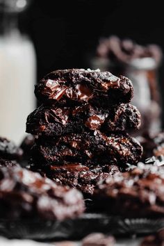 chocolate cookies stacked on top of each other in front of a bottle of milk and glass of milk