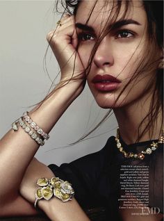 a woman with her hair blowing in the wind, wearing bracelets and necklaces