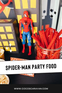 a spider man party food table with popcorn and toy figurines in the background