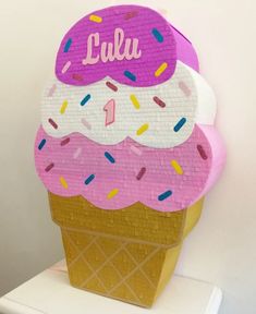 an ice cream cone with pink frosting and sprinkles is on display