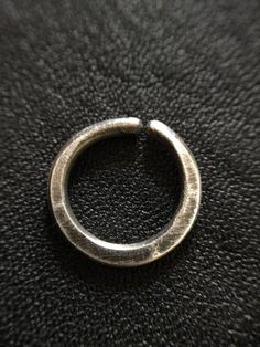 a metal ring sitting on top of a black leather surface with the end cut out